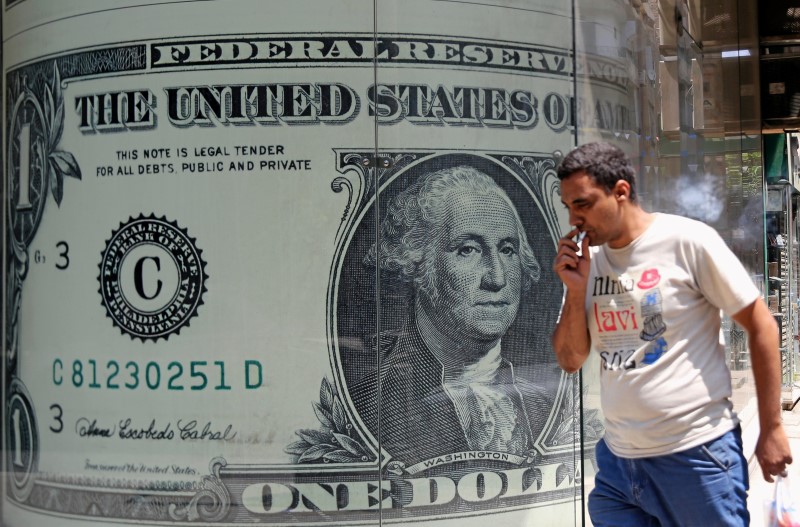 © Reuters. A man walks past a currency exchange bureau advertisement showing images of the U.S dollar and other currencies in Cairo