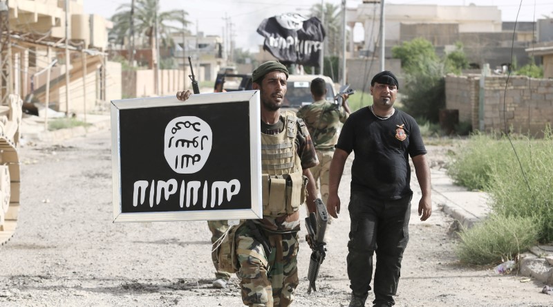 © Reuters. Shi'ite fighters hold an image of the Islamic State flag after clashes with IS militants in Saqlawiya