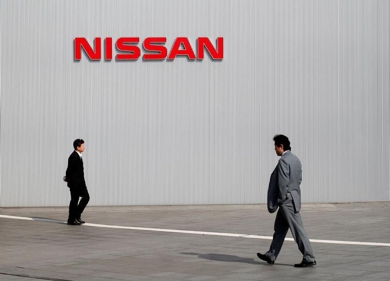 © Reuters. Men walk past a Nissan Motor Co logo at the company's global headquarters in Yokohama