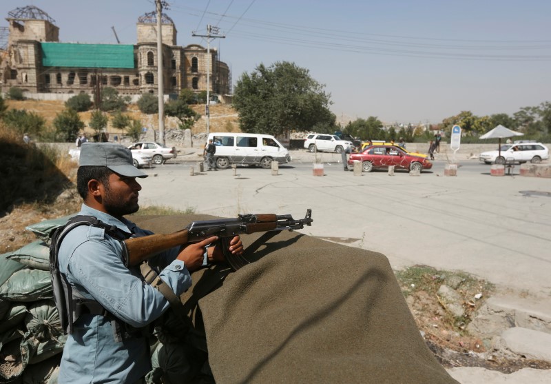 © Reuters. An Afghan policeman keeps watch at a checkpoint near the site of kidnapping in Kabul