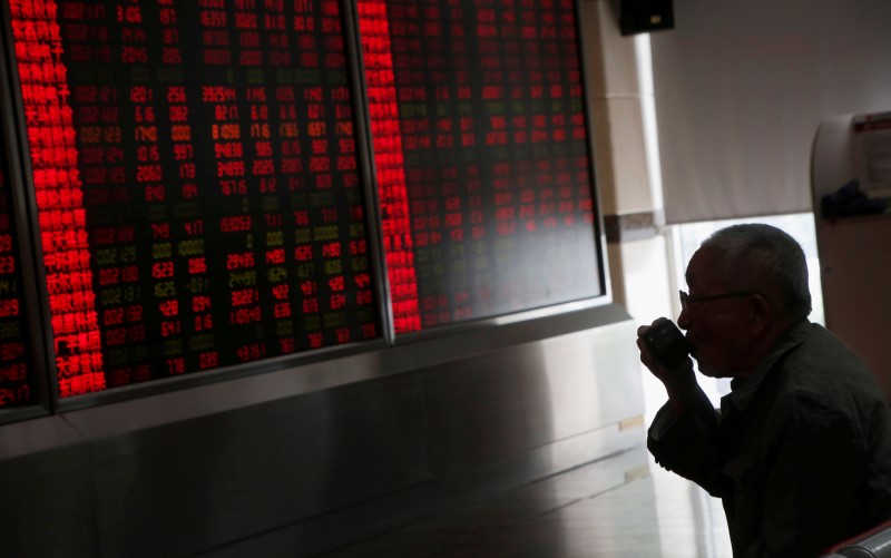 © Reuters. A man drinks a cup of tea in front of an electronic board at a brokerage house in Beijing