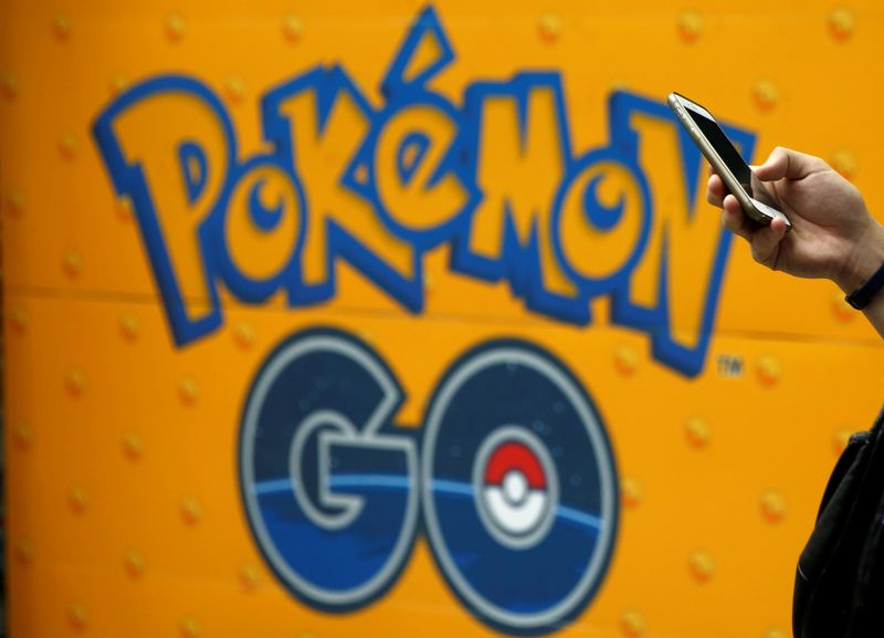 © Reuters. A man uses a mobile phone in front of an advertisement board bearing the image of Pokemon Go at an electronic shop in Tokyo