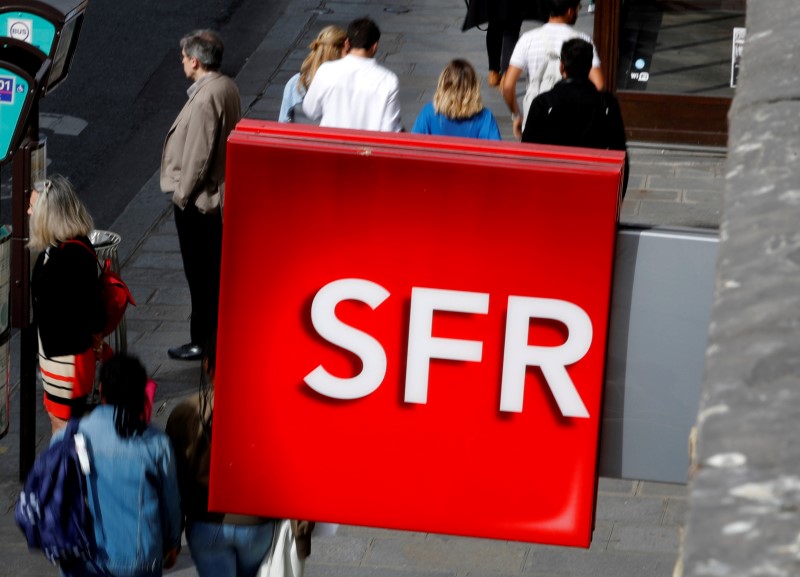 © Reuters. People walk under the logo of French telecoms operator SFR in Paris