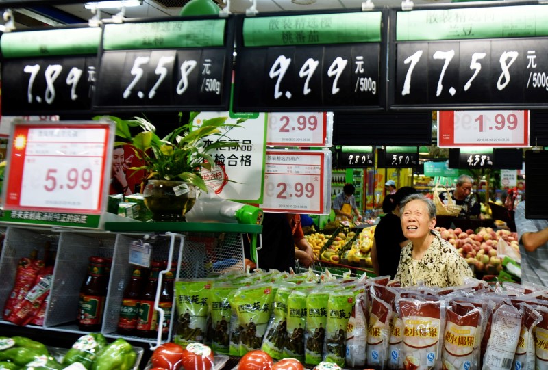 © Reuters. A woman looks at boards showing prices at a supermarket in Hangzhou