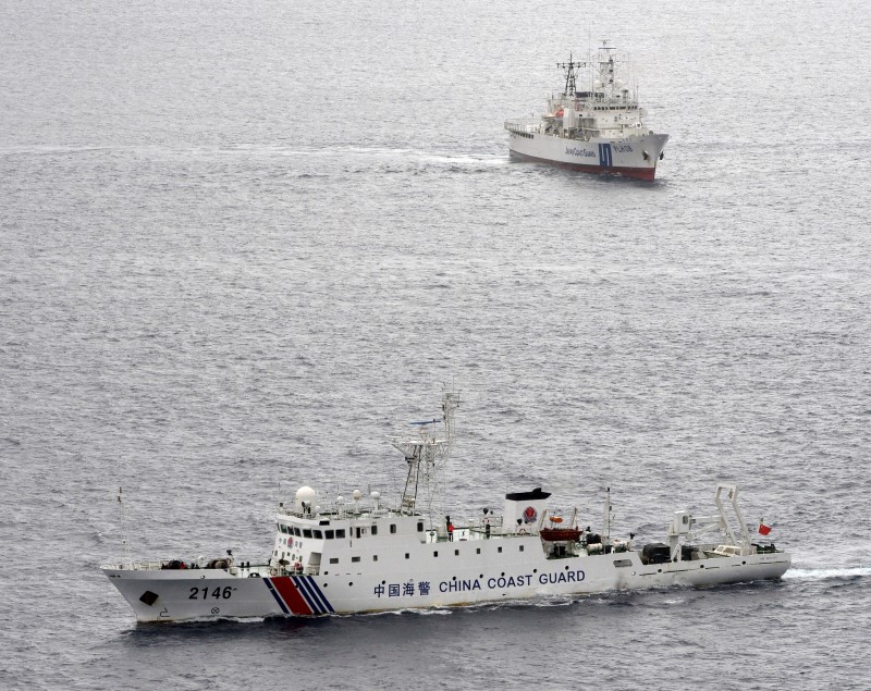 © Reuters. Navio da guarda costeira chinesa navegando em frente navio da guarda costeira japonesa no Mar do Leste da China