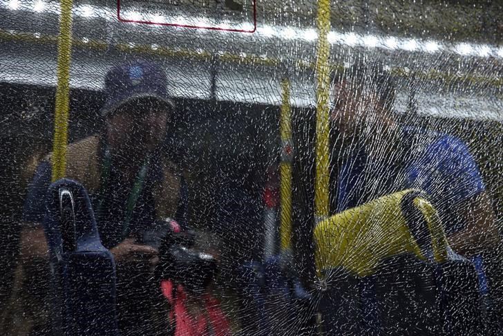 © Reuters. Journalists look at a broken window on an official media bus after it shattered in Rio de Janeiro