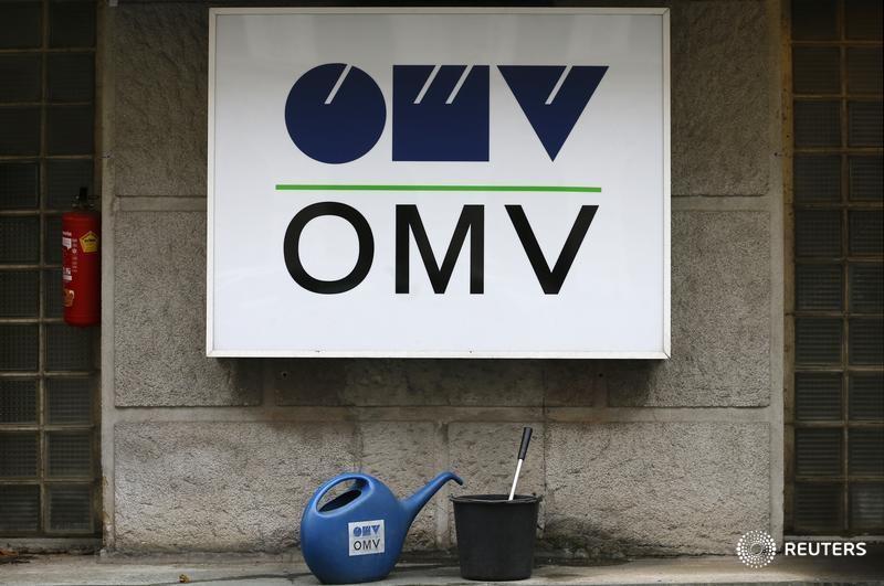 © Reuters. Watering cans are placed in front of the logo of Austrian energy group OMV at a gas station in Vienna