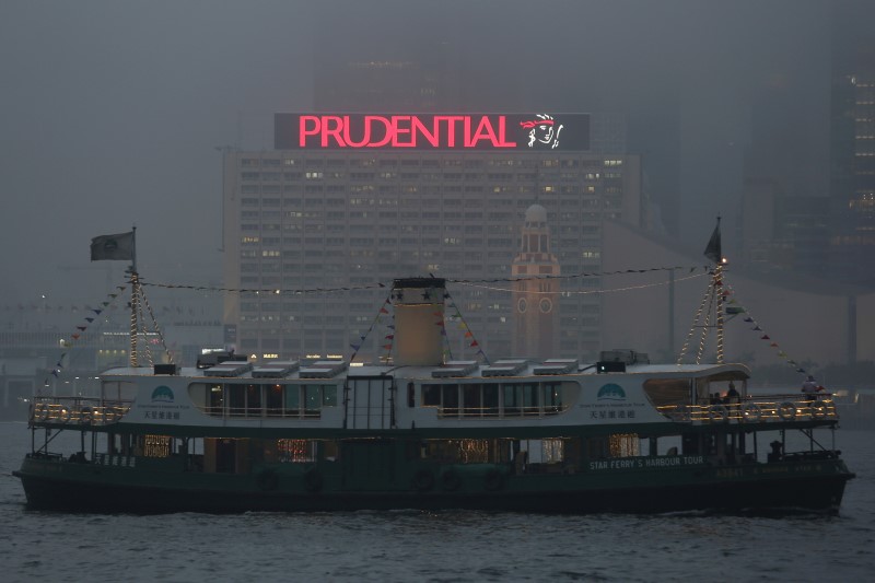 © Reuters. A ferry sails past an advertisement of Prudential Assurance under foggy weather at the Victoria Harbour in Hong Kong