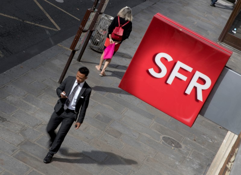 © Reuters. People walk under the logo of French telecoms operator SFR in Paris