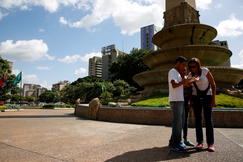 © Reuters. Carlos Reina, his mother Leida Castillo and his sister Cyndia, play the augmented reality mobile game "Pokemon Go" with his cell phone camouflaged in a book due to concerns about theft in Caracas