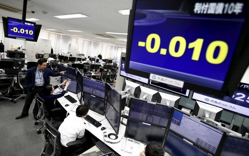 © Reuters. Employees of a foreign exchange trading company work under monitors displaying the 10-year Japanese government bond yield in Tokyo