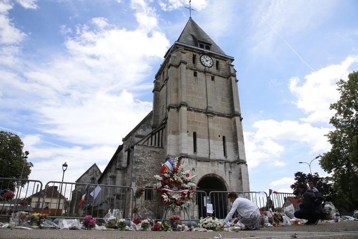 © Reuters. A woman places flowers to pay tribute to French priest Father Jacques Hamel outside the parish church at Saint-Etienne-du-Rouvray