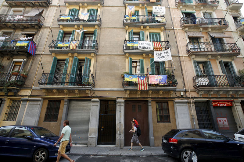 © Reuters. Banners against touristic apartments hang from balconies as people walk past them at Barceloneta neighborhood in Barcelona