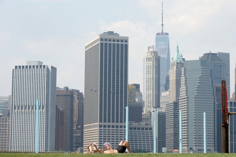 © Reuters. The skyline of lower Manhattan is seen as people lay on the grass in Brooklyn Bridge Park in the Brooklyn borough of New York City