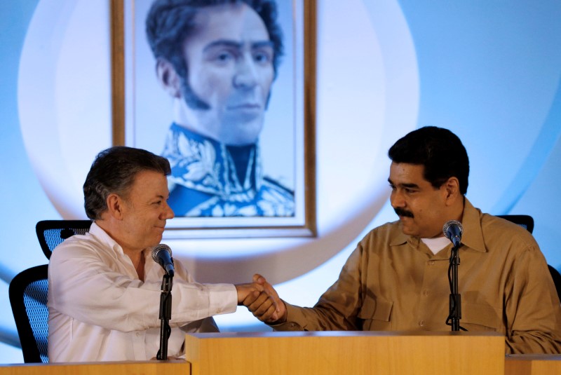 © Reuters. Venezuela's President Maduro and Colombia's President Santos shake hands in front of a painting of South American independence leader Simon Bolivar, during their meeting at Macagua Hydroelectric compound in Puerto Ordaz