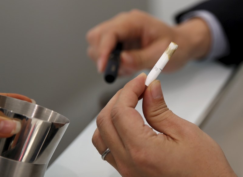 © Reuters. A customer takes off a filter after trying a Philip Morris' "iQOS" smokeless tobacco at an iQOS store in Tokyo