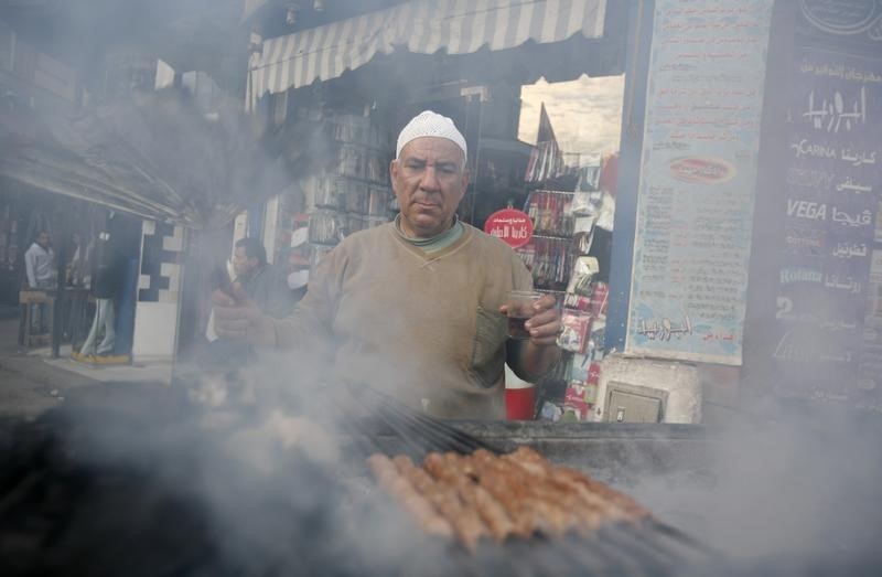 © Reuters. Мужчина готовит мясо на улице Каира