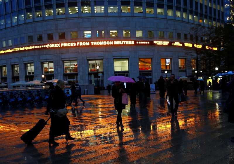 © Reuters. Workers walk in the rain at the Canary Wharf business district in London