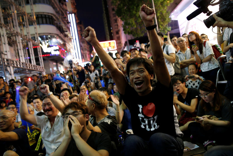 © Reuters. Supporters of the Hong Kong badminton team react as they watch the live broadcast of the Rio Olympics mixed doubles badminton match between Hong Kong and China at Mongkok shopping district in Hong Kong