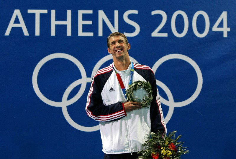 © Reuters. Phelps of the U.S. smiles with his gold medal in the men's 200 individual medley at the Athens 2004 ...