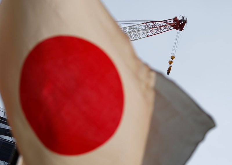 © Reuters. A crane at a construction site is seen behind Japan's national flag in Tokyo