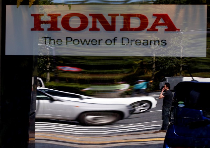 © Reuters. Man is reflected on a window at Honda Motor's showroom in Tokyo