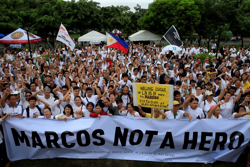 © Reuters. Protesters display a banner while giving the thumbs-down as they denounce the planned burial of late dictator Ferdinand Marcos at the Libingan ng mga Bayani (Heroe's Cemetery) during a protest at a park in metro Manila