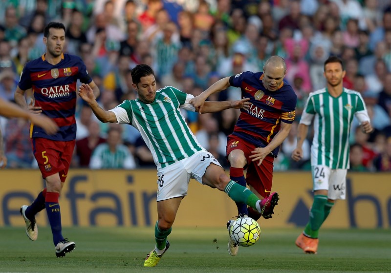 © Reuters. Barcelona's Andres Iniesta and Real BetisÕ Alvaro Cejudo in action