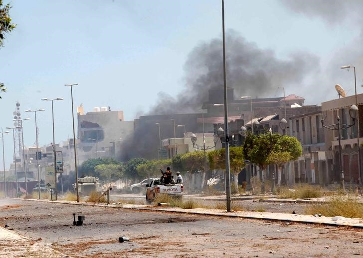 © Reuters. Fighters ride a pickup truck as smoke rises during a battle with Islamic State fighters in neighborhood Number Two in Sirte