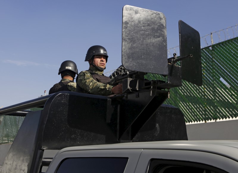 © Reuters. Mexican soldiers stand guard atop a vehicle on a street awaiting the arrrival of recaptured drug lord Joaquin "El Chapo" Guzman at the Navy's airstrip in Mexico City, Mexico