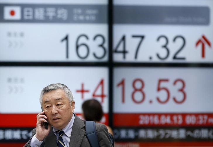 © Reuters. A man walks in front of an electronic board showing Japan's Nikkei average outside a brokerage in Tokyo