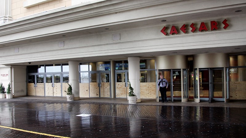 © Reuters. A security guard stands outside the entrance of Caesar's Casino on the Atlantic City boardwalk, with doors covered with sheets of plywood for protection from Hurricane Sandy as it approaches