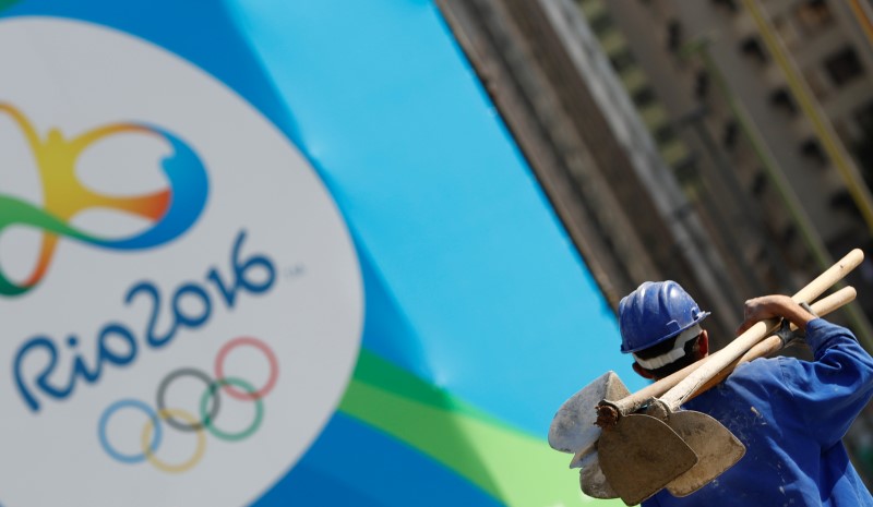 © Reuters. A construction worker walks by a logo of the Rio 2016 Olympics in Rio de Janeiro