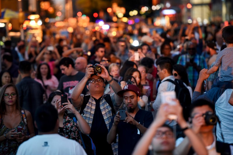 © Reuters. People crowd 42nd Street near Times Square to take pictures as the sun sets over Manhattan aligned exactly with the streets in a phenomenon known as "Manhattanhenge"