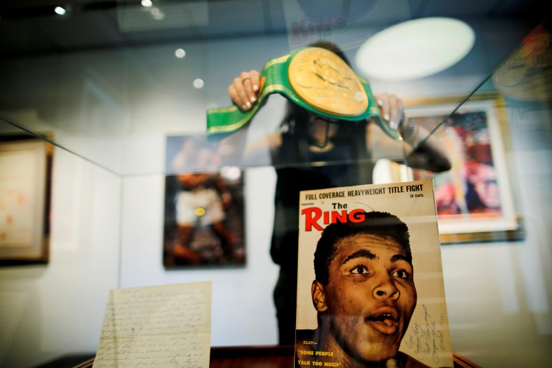 © Reuters. A woman arranges the Iconic 'Rumble in the Jungle' belt of late boxing champion Muhammad Ali at Heritage Auctions house in Manhattan, New York