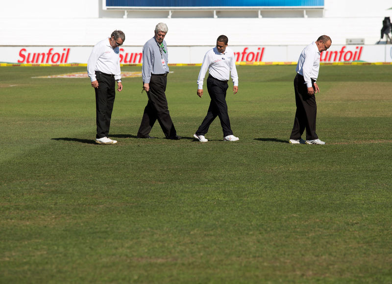 © Reuters. The umpires and ground staff inspect the playing surface after heavy overnight rain on the third day of the first cricket test match between South Africa and New Zealand in Durban