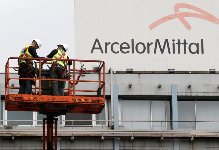 © Reuters. Workers stand near the logo of ArcelorMittal at the steel plant in Ghent