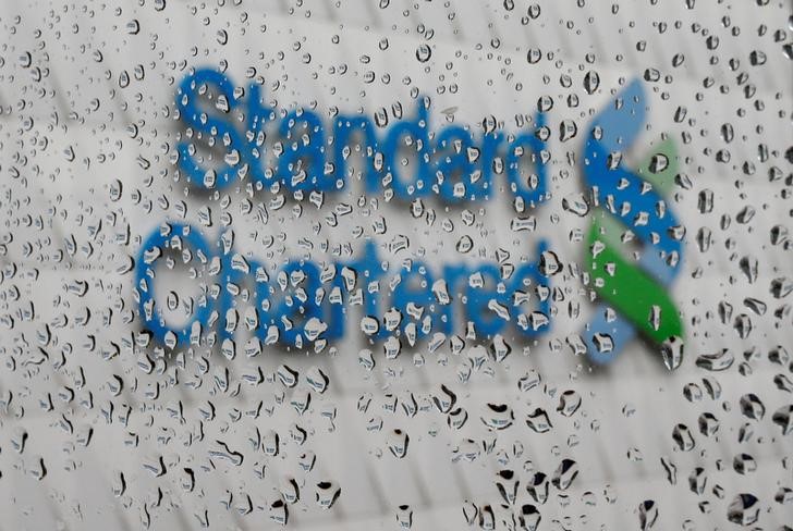 © Reuters. A Standard Chartered logo at its headquarters is seen through a window with raindrops, in Hong Kong