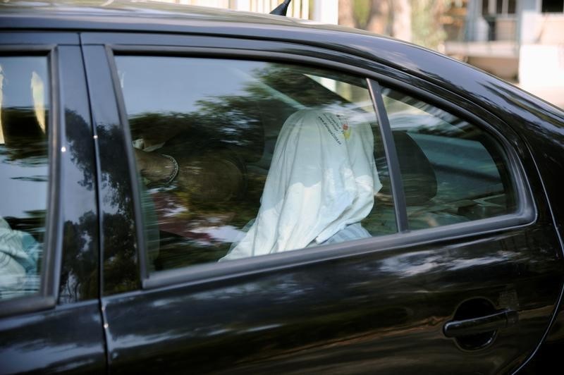 © Reuters. One of the eight Turkish soldiers, who fled to Greece in a helicopter and requested political asylum after a failed military coup against the government, is seen in a police car with his face covered, after his interview for asylum in Athens