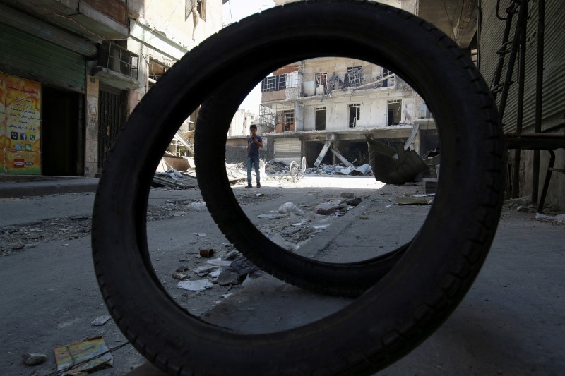 © Reuters. A boy walks past damaged shops and buildings in a rebel-held area of Aleppo