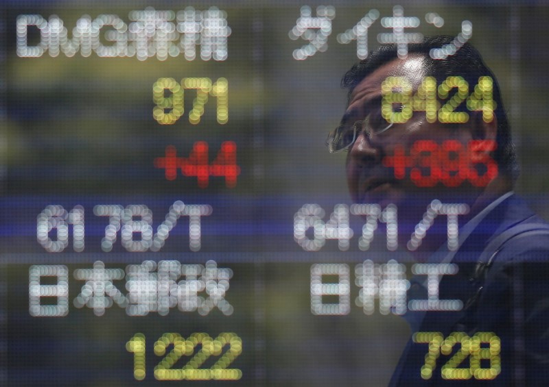 © Reuters. A man is reflected on a stock quotation board outside a brokerage in Tokyo