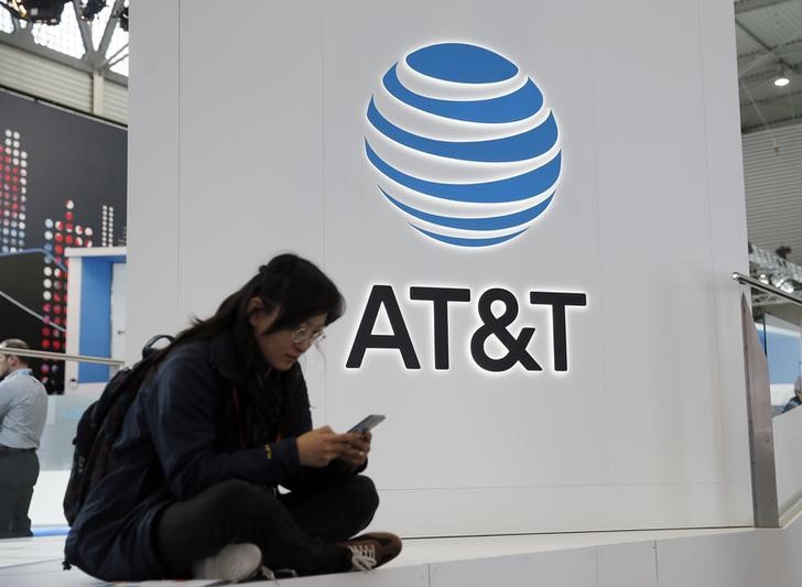 © Reuters. A woman looks at her mobile next to AT&T logo during the Mobile World Congress in Barcelona