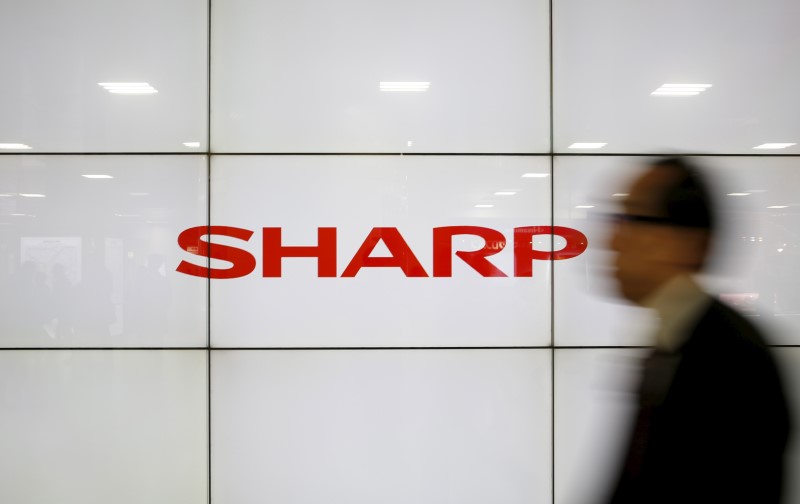 © Reuters. A man walks past Sharp Corp's liquid crystal display monitors showing the company logo in Tokyo