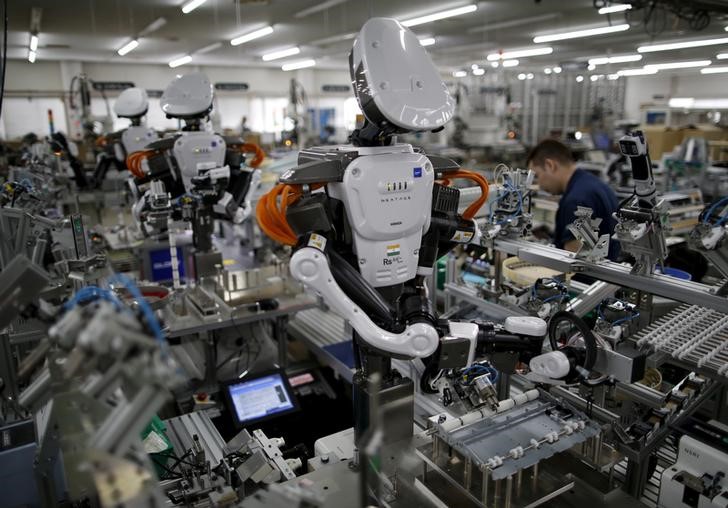 © Reuters. Humanoid robots work side by side with employees in the assembly line at a factory of Glory Ltd., a manufacturer of automatic change dispensers, in Kazo, north of Tokyo