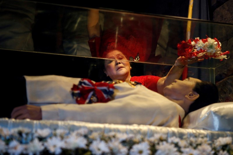 © Reuters. Former first lady Imelda Marcos offers flowers on the glass coffin of her husband in Batac