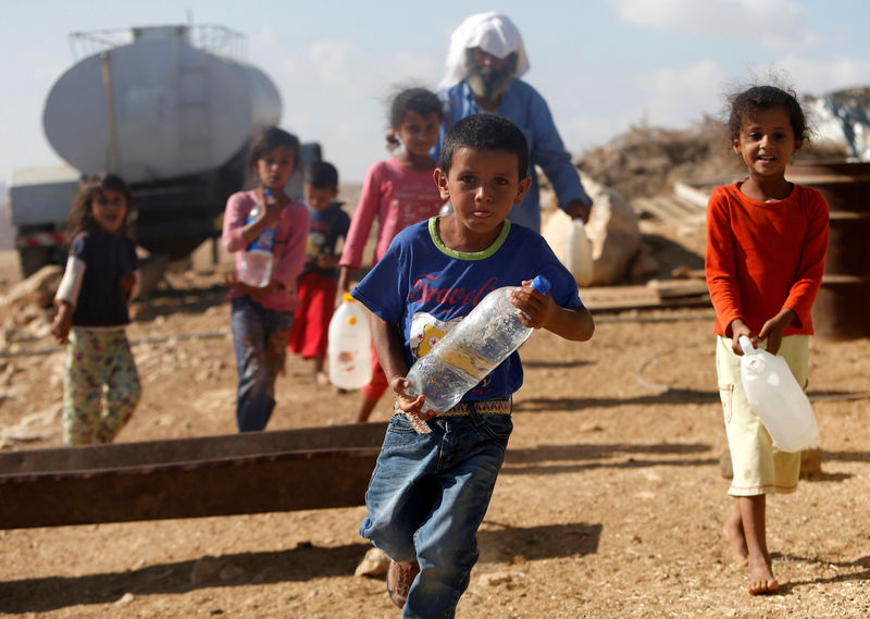 © Reuters. Palestinian children carry water bottles near their house on the outskirts of the West Bank village of Yatta