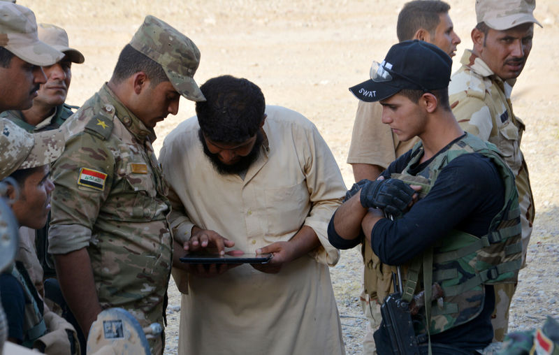 © Reuters. A displaced man from south of Mosul gives the coordinates of Islamic State militants to Iraqi army, south of Mosul