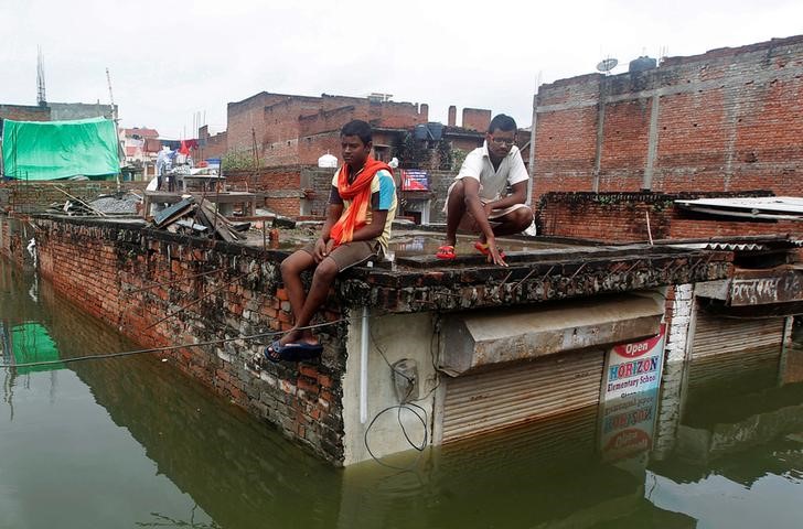 © Reuters. Homens em teto de local atingido por inundações em Allahabad, na Índia