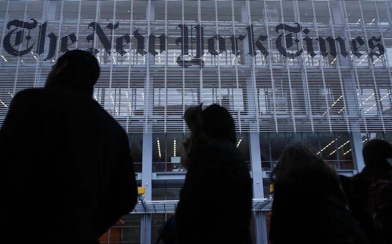 © Reuters. People line up for taxi across the street from the New York Times head office in New York