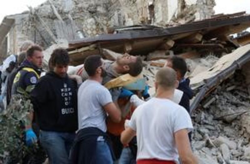 © Reuters. Uomo messo in salvo ad Amatrice dopo il terremoto di stanotte.